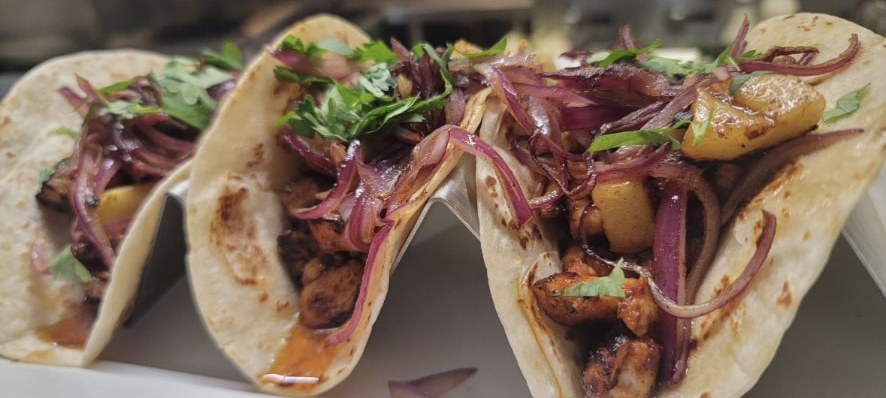 Three al pastor tacos with grilled pineapple, red onion and cilantro